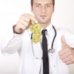 A doctor holding grapes giving a thumbs up sign